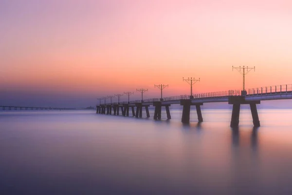 Sebuah Jembatan Atas Danau Yang Tenang Selama Matahari Terbenam Berwarna — Stok Foto