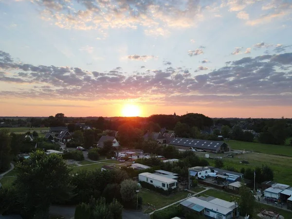 金色の夕日を眺めながら建物や緑の木々が並ぶ小さな町を空中で撮影 — ストック写真