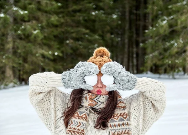 暖かい冬の帽子と手袋の女の子雪の森の中で彼女の目の前に2つの雪玉を保持 — ストック写真