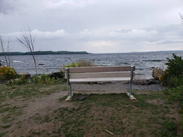 一张特写镜头 是一张木制长椅的特写镜头 它坐落在一片草地上 面对着大海 — 图库照片