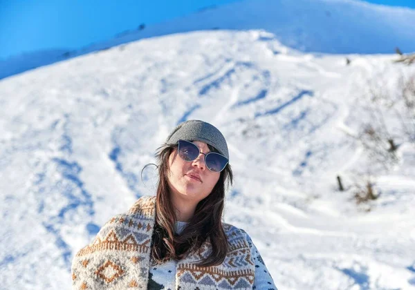 雪の山の美しい景色を眺めながらサングラスとスカーフを持つ女性観光客 — ストック写真