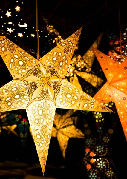 クリスマスマーケットに掛けられながら輝く黄色の星の垂直方向の景色 — ストック写真