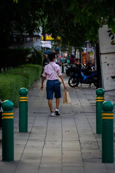 一个男人拿着纸袋走在街上的一张垂直的照片 泰国曼谷 — 图库照片