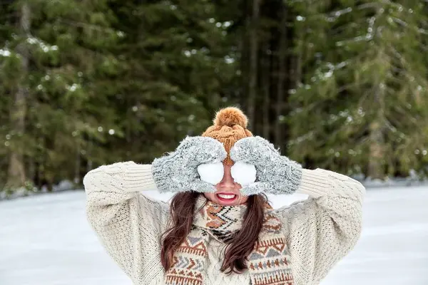 在雪地的森林里 一个戴着温暖的冬帽和手套 头戴两个雪球 面带微笑的女孩 — 图库照片