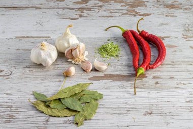 Biber, sarımsak, defne yaprağı ve ahşap bir masanın üzerinde kekik resmi.