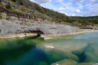 A landscape of the Pedernales Falls State Park under a blue cloudy sky and sunlight in Texas clipart