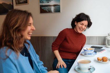 Kafede oturan, kahve içip sohbet eden iki kadın.