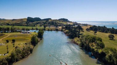Güneşli bir günde yeşil tarlalarla çevrili teknelerle dolu bir nehir.