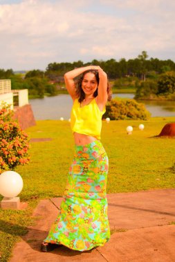 Parkta gün ışığında resim çektiren güzel, genç bir İspanyol hanımın dikey görüntüsü.