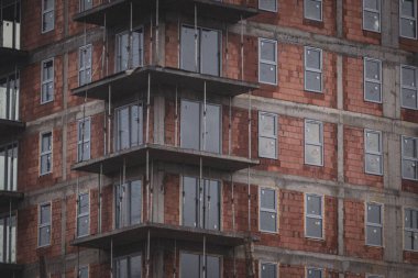 Yeni yapılmış pencereleri olan yarı inşa edilmiş bir apartman manzarası.