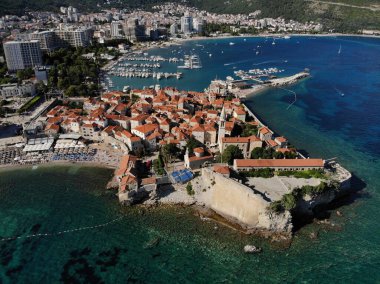 Budva şehrinin deniz manzaralı ve Karadağ 'da limana yanaşmış tekneleri olan insansız hava aracı manzarası