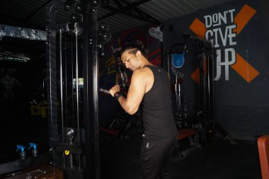 Hintli bir erkek spor salonunda kaldırma egzersizi yapıyor.