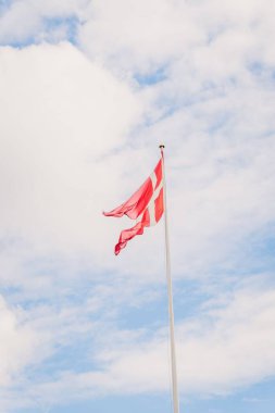 Arka planda mavi gökyüzü olan Danimarka Bayrağının dikey çekimi