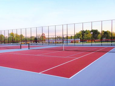 İnanılmaz kırmızı tenis kortu, beyaz çizgiler ve gri penyball çizgileri.