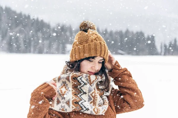 一个穿着舒适的冬衣和围巾的女人在雪地里俯瞰着大地 — 图库照片
