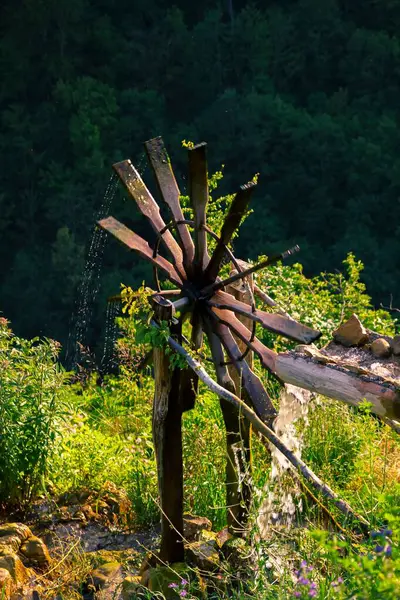 太陽の下で緑の丘の上に古い水車の垂直ショット — ストック写真