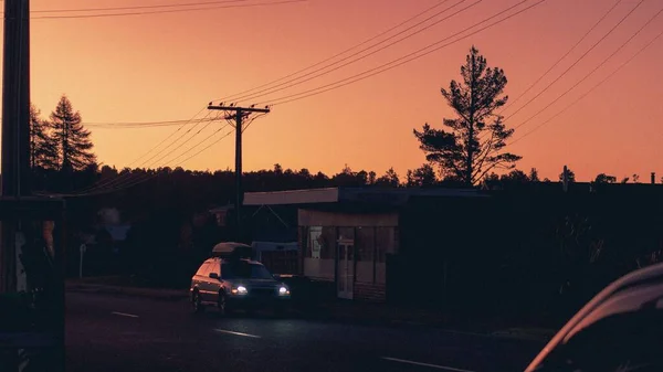 オレンジ色の夕日の中 車が乗っている通りの景色 — ストック写真