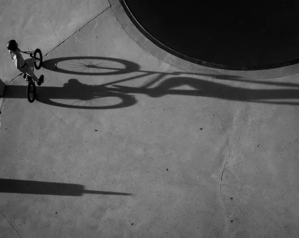 長い影を投げかけるスケートパークでTxバイカーの空中グレースケールショット — ストック写真