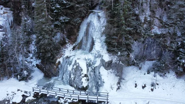 在冬季公园里被冰雪覆盖的冰冻瀑布和桥梁的空中拍摄 — 图库照片