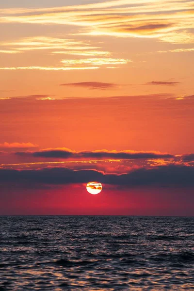 夜の海の上の息をのむような赤い夕日の垂直ショット — ストック写真