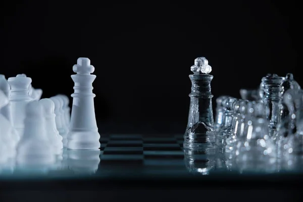 stock image A closeup shot of crystal chess pieces on a glass board on black background