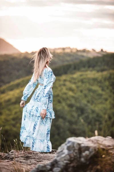 丘の近くに立っている若い女性の垂直ショット — ストック写真