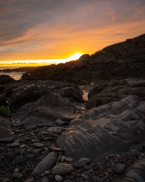 夕阳西下 海岸上布满岩石的山脉 背景为大海的垂直照片 — 图库照片