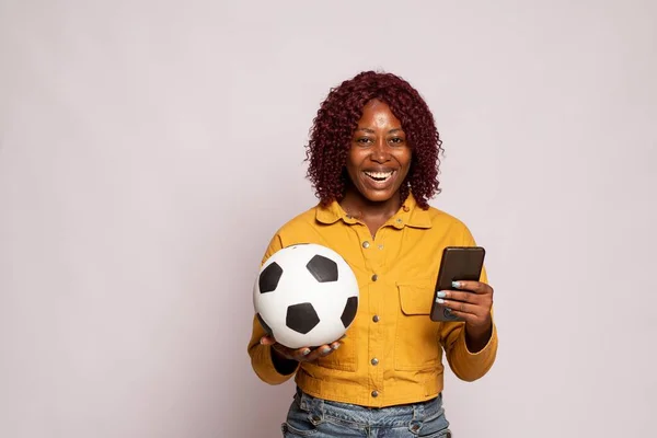 Bonita Senhora Preta Segurando Uma Bola Futebol Usando Seu Telefone — Fotografia de Stock