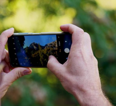 Beyaz ellerin seçici odak noktası manzaranın fotoğraflarını çekiyor.