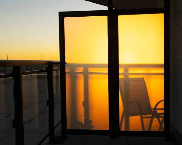 日落时玻璃门后一张空椅子的轮廓 — 图库照片