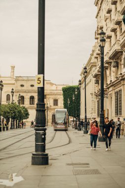 İspanya, Sevilla 'da bir tramvayın yanında yürüyen insanların dikey görüntüsü.