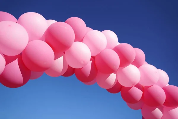 An arch made of pink balloons against the blue sky in closeup