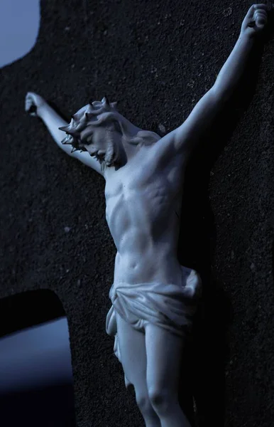 黒い十字架にかけられたイエス キリストの彫像の垂直ショット — ストック写真
