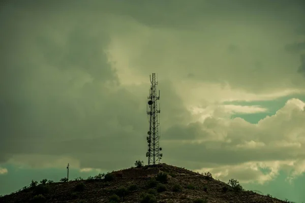 Egy Telekommunikációs Torony Egy Domb Tetején Egy Felhős Égbolttal Szemben — Stock Fotó