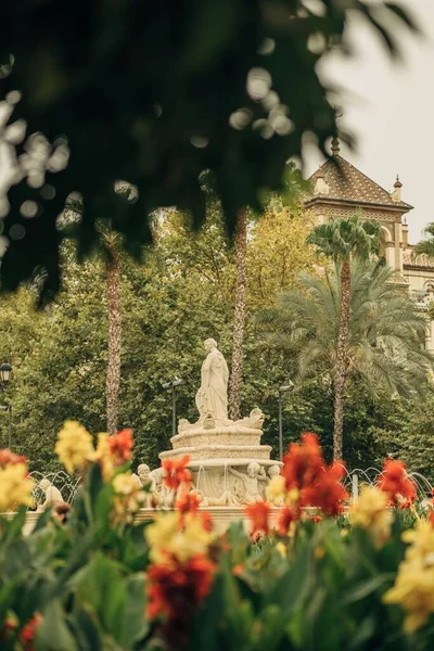 Egy Függőleges Felvétel Egy Szoborról Egy Parkban Virágokkal Háttérben Sevillában — Stock Fotó
