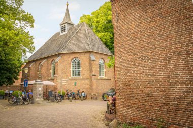 Hollanda 'nın Gelderland kentindeki Bronkhorst Şapeli' nin yakınındaki kafede oturan ve bisikletle gezen insanların sokak görüntüsü.