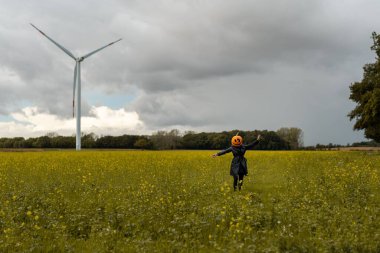Balkabağı kafalı bir dişi bahçede poz veriyor, elinde bir balkabağı tutuyordu.