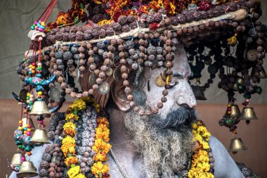 Siyah arka planda renkli bir şapkayla boyanmış bir Naga Sadhu portresi.