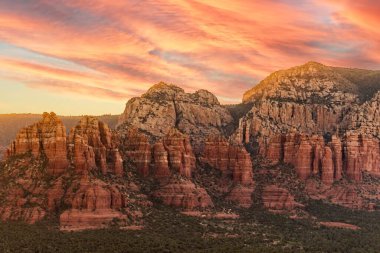 Sedona 'da doğal kaya oluşumlarının ve gün batımında pembe gökyüzünün manzaralı bir görüntüsü.