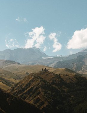 Parlak mavi gökyüzüne karşı dağlardaki bir kilisenin nefes kesici dikey görüntüsü.