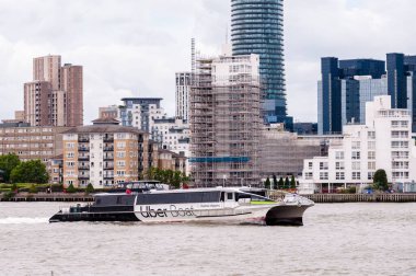Londra 'daki Greenwich Yarımadası' ndaki modern yerleşim yerlerinin yakınında Thames nehrinde seyreden bir gemi.