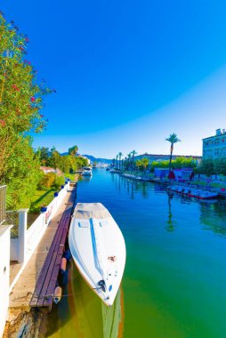 Mavi gökyüzünün altındaki bir nehrin yüzeyindeki bir teknenin dikey görüntüsü.