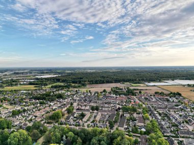 Bulutlu bir gökyüzüne karşı yeşil ormanlarla çevrili bir şehir.