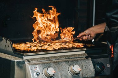 Erkek bir aşçının sobada barbekü yaparken gündüz görüntüsü.