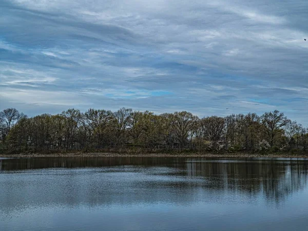 Piękny Widok Spokojne Jezioro Otoczone Drzewami Przeciwko Błękitnym Zachmurzonym Niebem — Zdjęcie stockowe
