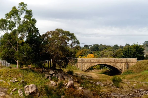 オーストラリアのビクトリア州ブライトにある草と岩のある乾燥したストリーム上の古い石の橋 — ストック写真