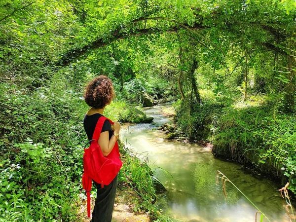 A landscape shot of a woman beside a river at the equipped park of Vicoli, in Abruzzo during the daytime