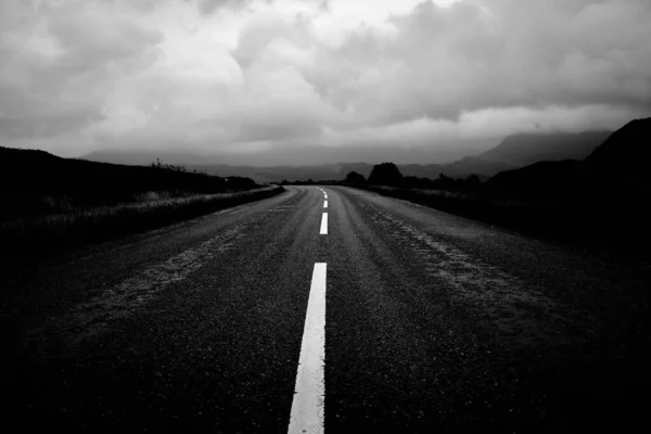 Greyscale Road Surrounded Field Rocky Smooth Mountains — Stock Photo, Image
