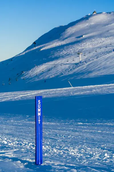 雪の山の頂上に置かれた青い標識の柱の垂直ショット — ストック写真