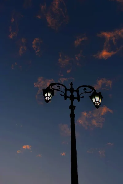 黑暗的街灯在阴沉沉的落日的天空下垂直拍摄的照片 — 图库照片